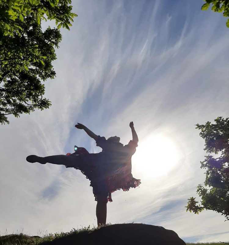 A silhouette of Catilin Paramor dancing freely in the sun