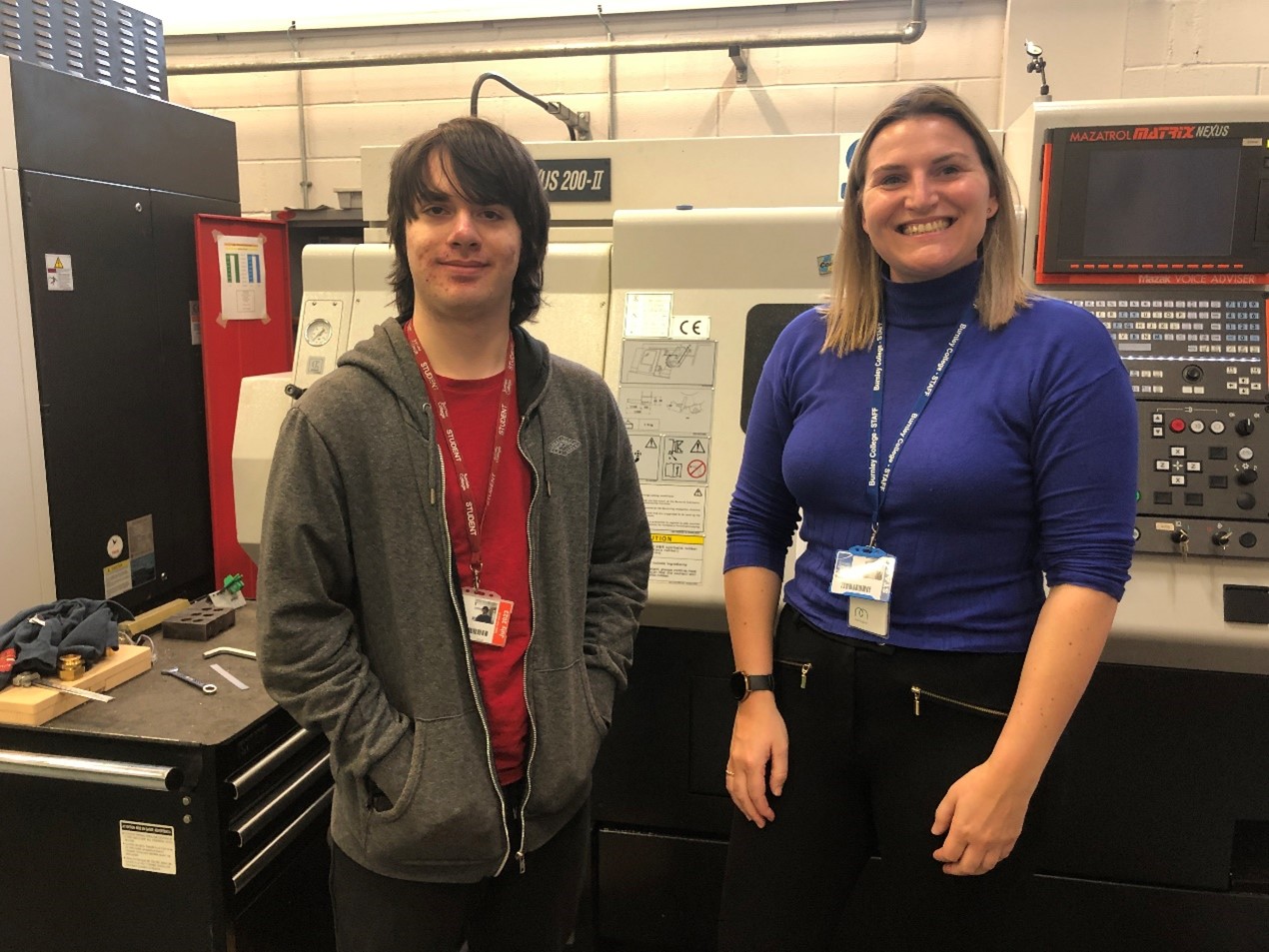 An engineering student and one of his senior lecturers stand in front of a CNC machine