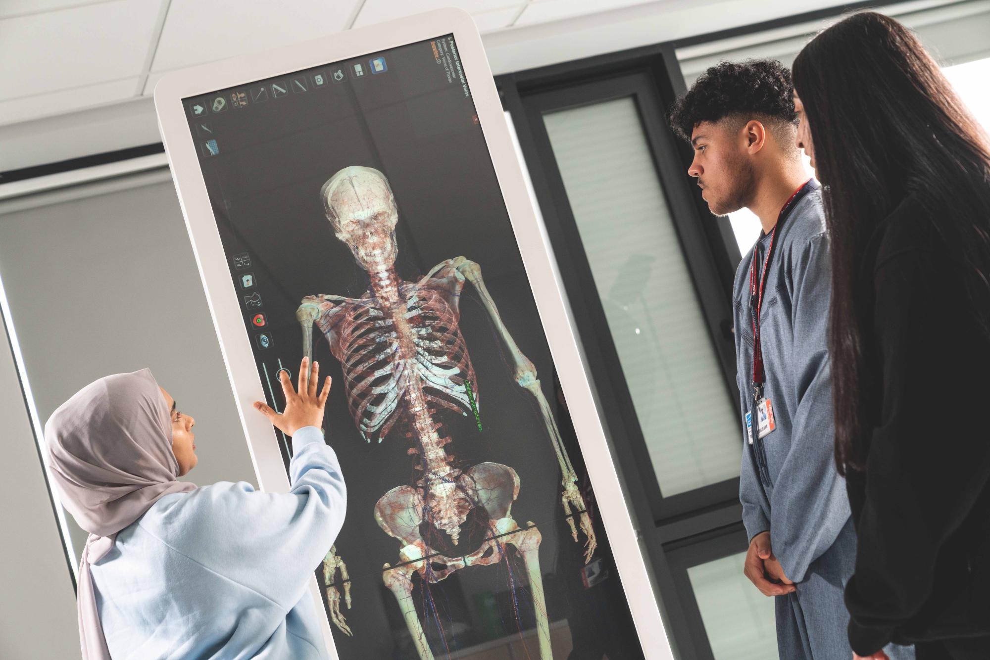 Three students working around a state of the art Anatomage table learning about human anatomy