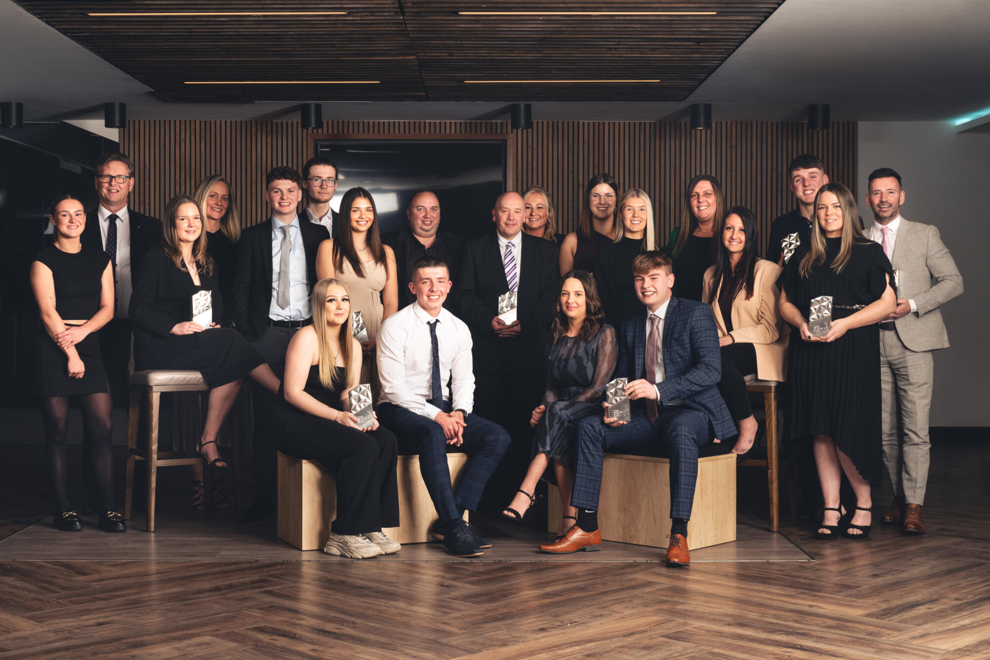 A group of young award winners in a group pose at a glamrous award ceremony