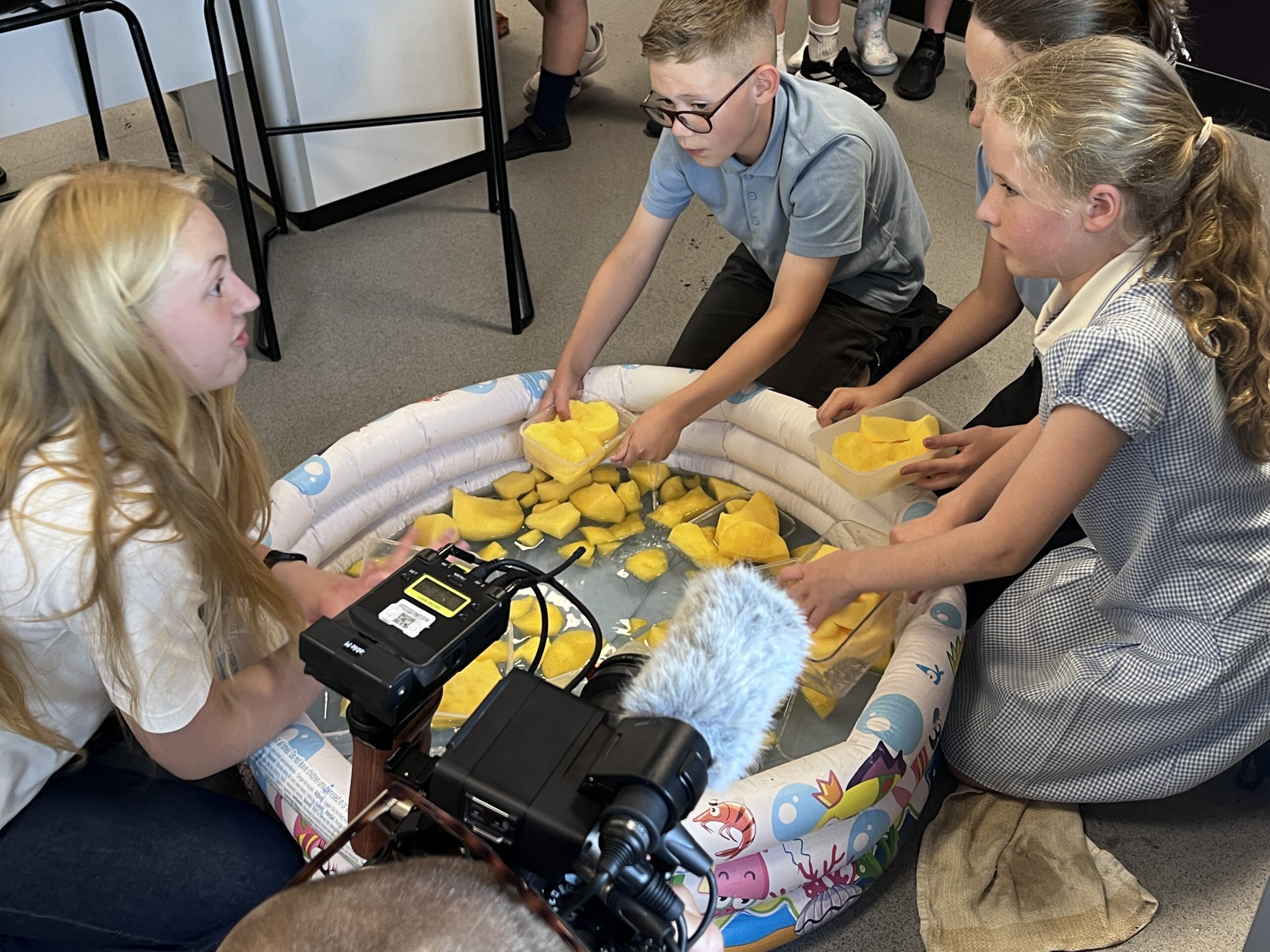 Primary pupils sit round a paddling pool of sponges
